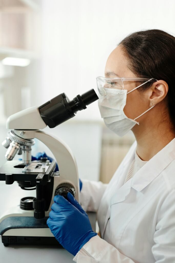 Woman in Mask Using Microscope